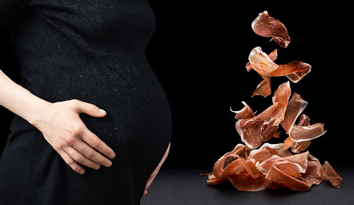 Mujer embarazada y plato de jamón serrano cortado en lonchas